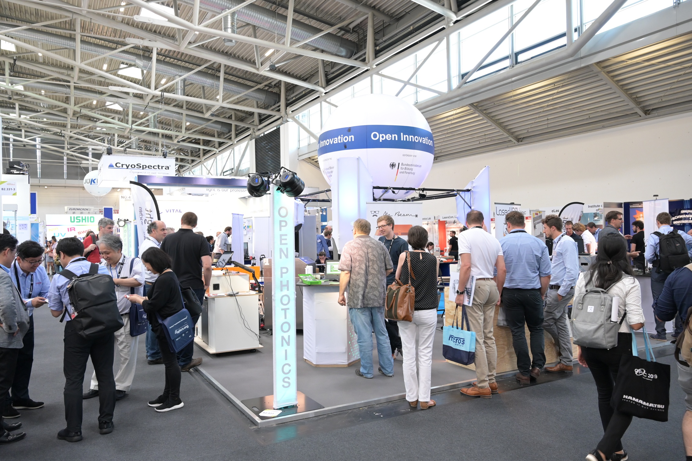 Viele Menschen auf einem Messestand mit vielen kleinen Ausstellungstischen und Exponatan