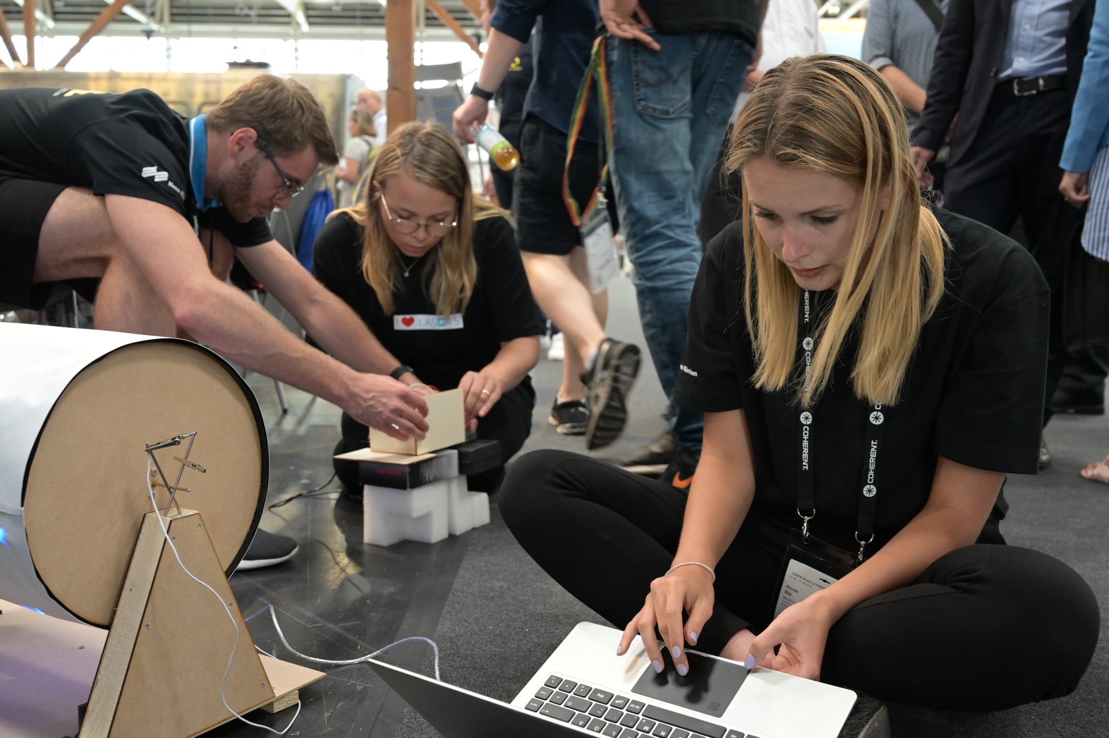 Junge Frauen und Männer sitzen auf dem Boden und arbeiten an einem Prototypen